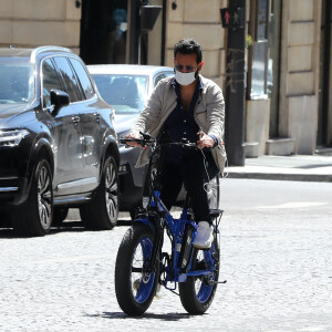 Exclusif - Cyril Hanouna se promène à vélo ( un vélo électrique de la marque Moov Way) et avec un masque de protection dans les rues de Paris pendant l'épidémie de Coronavirus Covid-19 le 20 mai 2020.