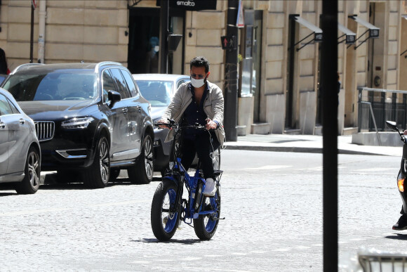 Exclusif - Cyril Hanouna se promène à vélo ( un vélo électrique de la marque Moov Way) et avec un masque de protection dans les rues de Paris pendant l'épidémie de Coronavirus Covid-19 le 20 mai 2020.