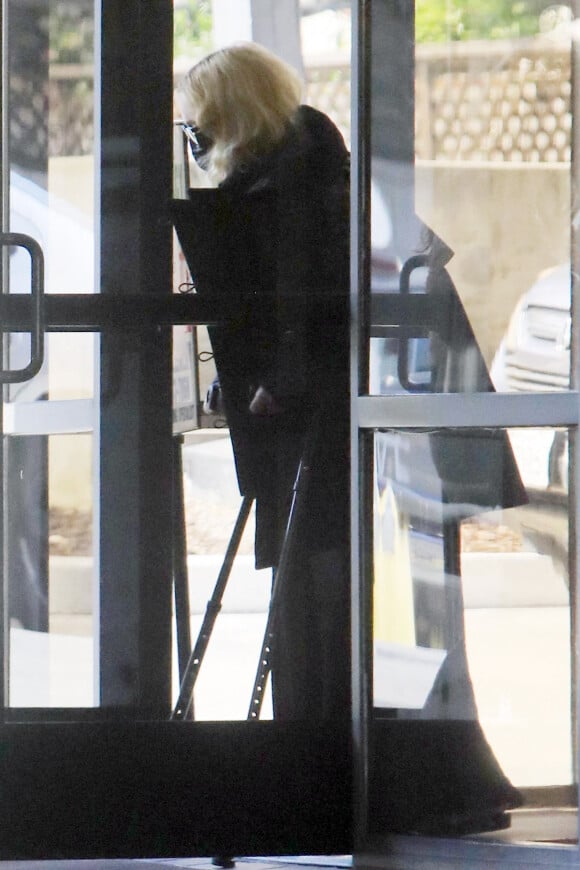 Exclusif - Madonna se déplace avec des béquilles et avec l'aide d'une assistante à la sortie d'un immeuble à Los Angeles pendant l'épidémie de coronavirus (Covid-19), le 22 juillet 2020. The ImageDirect / Bestimage