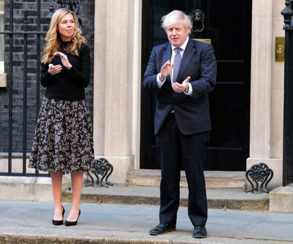 Boris Johnson et sa compagne Carrie Symonds, jeunes parents, applaudissent le personnel soignant pendant l'épidémie de coronavirus (Covid-19) devant leur résidence à Londres. En mai 2020.