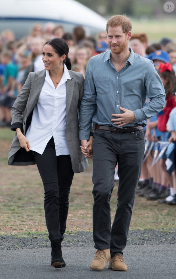 Le prince Harry et sa femme Meghan Markle (enceinte), accueillis par des élèves australiens à leur arrivée à Dubbo, lors de leur première tournée officielle dans le Pacifique, cinq mois après leur mariage.