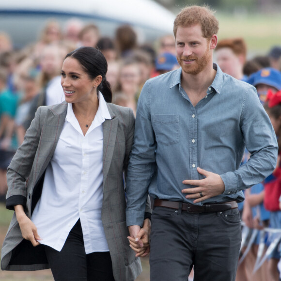 Le prince Harry et sa femme Meghan Markle (enceinte), accueillis par des élèves australiens à leur arrivée à Dubbo, lors de leur première tournée officielle dans le Pacifique, cinq mois après leur mariage.
