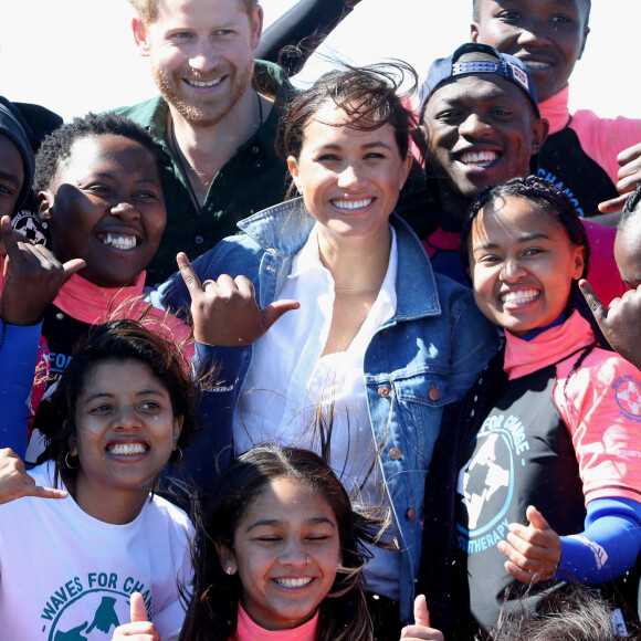 Le prince Harry, duc de Sussex, et Meghan Markle, duchesse de Sussex rencontrent les membres de "Waves for Change" un organisme de bienfaisance qui travaille avec les surfeurs locaux sur la plage de Monwabisi au Cap lors de leur 2ème journée en Afrique du Sud, le 24 septembre 2019.