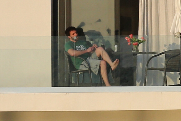 Ben Affleck fume une cigarette sur le balcon de la maison qu'il loue avec Jennifer Lopez à Miami le 25 mai 2021. 
