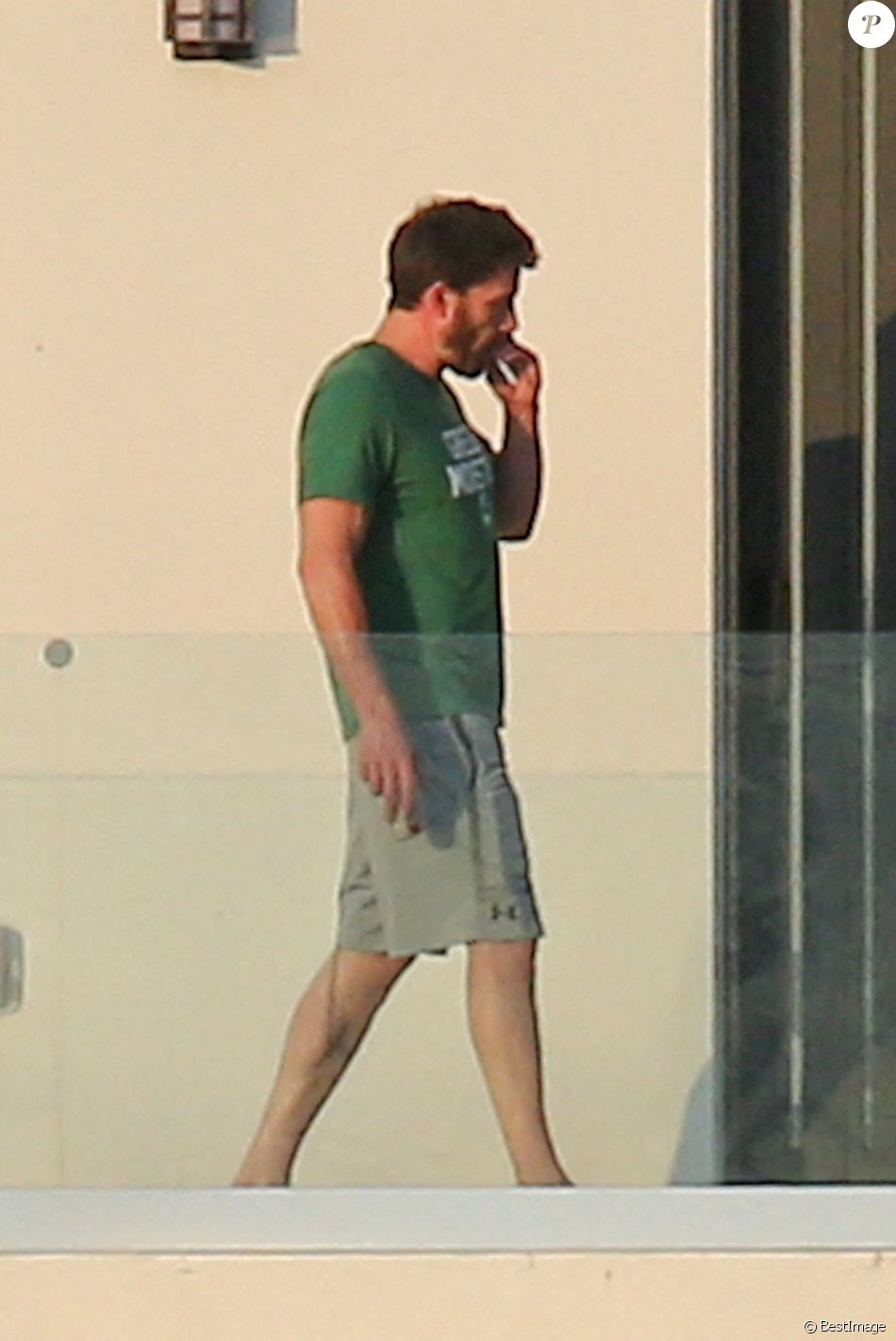Ben Affleck fume une cigarette sur le balcon de la maison qu'il loue avec Jennifer Lopez à Miami le 25 mai 2021.
