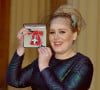 La chanteuse Adele (Adele Adkins) pose avec sa médaille (MBE) lors d'une cérémonie au palais de Buckingham à Londres, le 19 décembre 2013.
