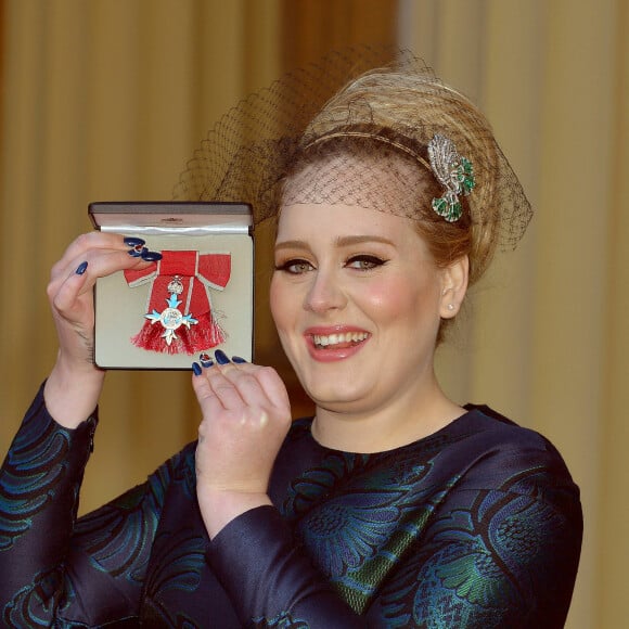 La chanteuse Adele (Adele Adkins) pose avec sa médaille (MBE) lors d'une cérémonie au palais de Buckingham à Londres, le 19 décembre 2013.