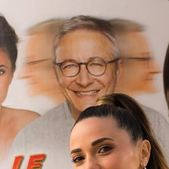 Capucine Anav devant une affiche de la pièce "Le Switch"