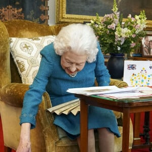 La reine Elisabeth II est rejointe par l'un de ses chiens, un Dorgi appelé Candy, alors qu'elle regarde une exposition de souvenirs de ses jubilés d'or et de platine dans la salle Oak du château de Windsor. Février 2022.