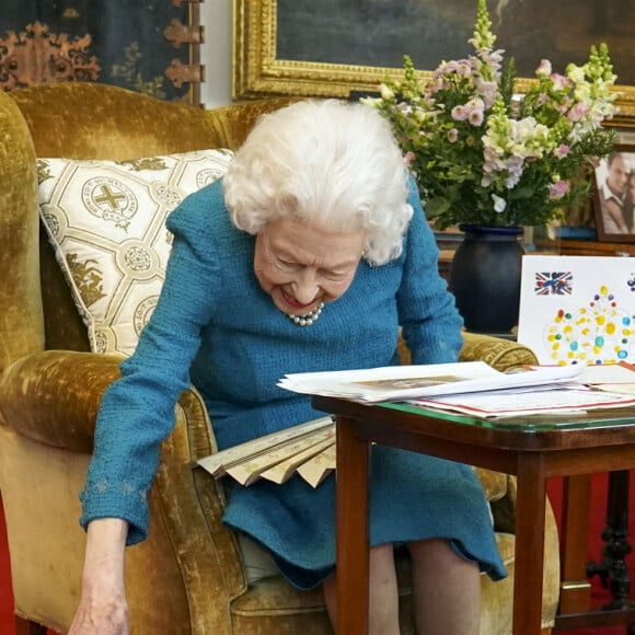 La reine Elisabeth II est rejointe par l'un de ses chiens, un Dorgi appelé Candy, alors qu'elle regarde une exposition de souvenirs de ses jubilés d'or et de platine dans la salle Oak du château de Windsor2022.