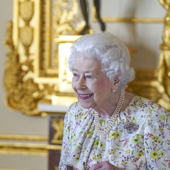 La reine Elisabeth II d'Angleterre parcourt l'exposition d'objets de la société d'artisanat britannique Halcyon Days, pour marquer son jubilé de platine, au château de Windsor, le 23 mars 2022.  Queen Elizabeth II smiles as she arrives to view a display of artefacts from British craftwork company, Halcyon Days, to commemorate the company's 70th anniversary in the White Drawing Room at Windsor Castle, Berkshire. Picture date: Wednesday March 23, 2022. 