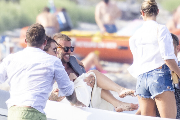 David Beckham et sa femme Victoria quittent la plage des Salins après avoir passé l'après-midi dans une résidence privée à Saint-Tropez le 23 juillet 2022. En grand gentleman, David prend sa femme dans les bras pour monter dans l'annexe du yacht ancré dans la baie pour éviter que sa belle ne mettre les pieds dans les algues échouées au bord de l'eau.