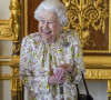 La reine Elisabeth II d'Angleterre parcourt l'exposition d'objets de la société d'artisanat britannique Halcyon Days, pour marquer son jubilé de platine, au château de Windsor, le 23 mars 2022. 