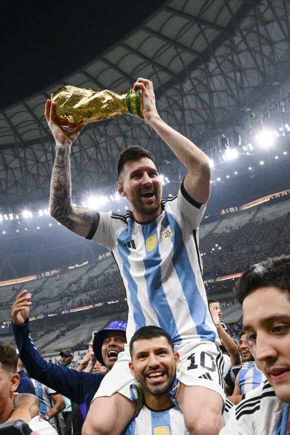 Lionel Messi soulevant le trophee de la Coupe du Monde et porte en triomphe par ses coequipiers - Remise du trophée de la Coupe du Monde 2022 au Qatar (FIFA World Cup Qatar 2022) à l'équipe d'argentine après sa victoire contre la France en finale (3-3 - tab 2-4). Doha, le 18 décembre 2022.