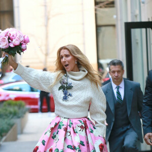Celine Dion rayonnante et très souriante dans un ensemble pull écru et jupe bouffante fleurie salue ses fans à la sortie de son hôtel à New York, le 8 mars 2020
