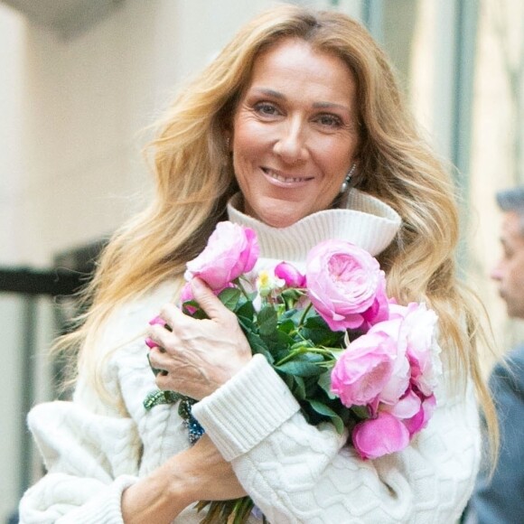 Celine Dion rayonnante et très souriante dans un ensemble pull écru et jupe bouffante fleurie salue ses fans à la sortie de son hôtel à New York