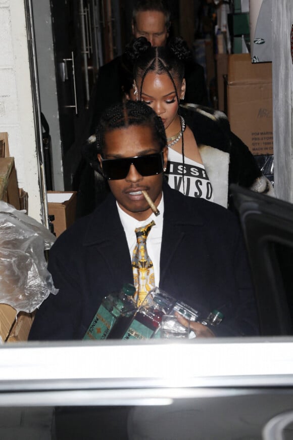 Exclusif - Rihanna et son compagnon A$AP Rocky, les mains pleines de son cognac "Mercer + Prince", quittent une soirée à Beverly Hills, le 19 décembre 2022. Elle porte des boucles d'oreilles de la marque Messika