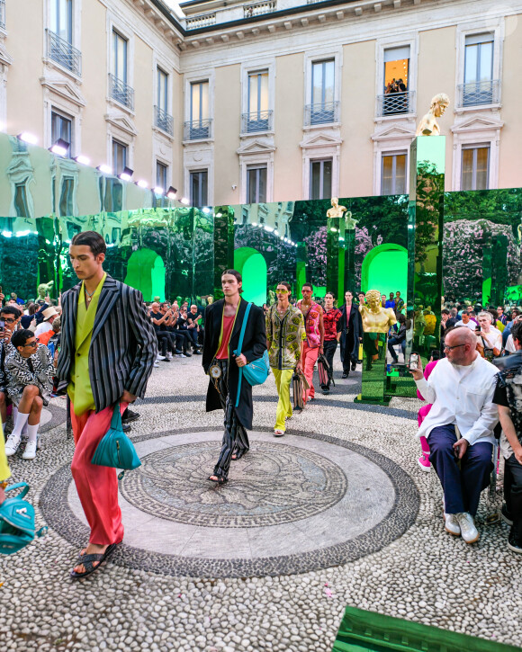 Sur deux d'entre elles, il prend la pose avec ses amis. 
Aurélien Enthoven (fils de C. Bruni - chemise rouge et noire) - Défilé Versace "Collection Prêt-à-Porter Homme Printemps/Eté 2023" lors de la Fashion Week de Milan (MLFW), le 18 juin 2022. 