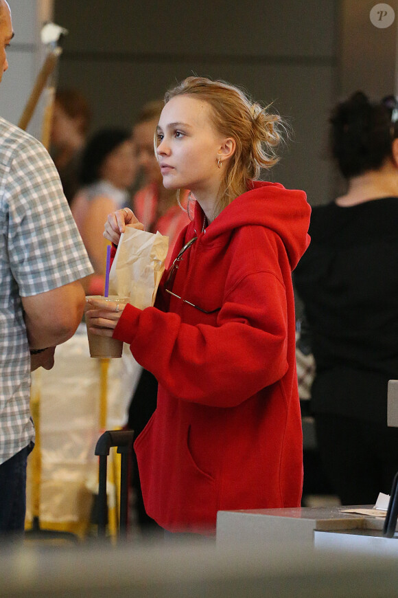 Lily-Rose Depp fait la queue au comptoir "The Coffee Bean" à l'aéroport de Los Angeles, commande puis mange un snack avec une boisson rapidement avant d'aller prendre un avion accompagnée de son garde du corps le 22 mai 2016.