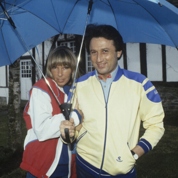 En France, Michel Drucker, avec sa femme Dany Saval, se promenant dans le jardin et s'abritant sous des parapluies © Michel Ristroph via Bestimage