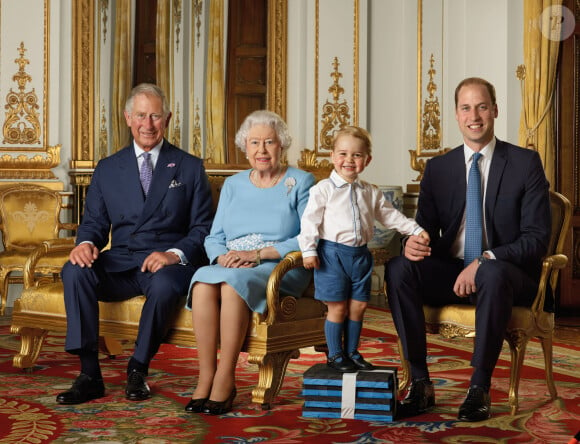 C'est le prince William puis le prince George. 
La reine Elisabeth II a posé, à l'occasion de son 90ème anniversaire, avec son fils le prince Charles, son petit-fils le prince William et son arrière petit-fils le prince George, pour quatre nouveaux timbres de la Royal Mail, au palais de Buckingham à Londres. 