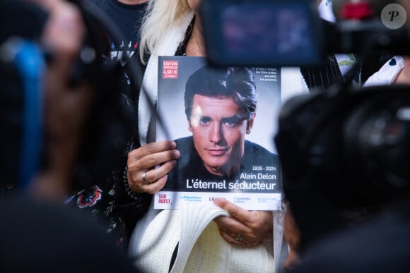 Les fans rendent hommage à Alain Delon devant la grille de sa propriété à Douchy-Montcorbon pendant ses obsèques le 24 août 2024. © Baptiste Autissier / Panoramic / Bestimage