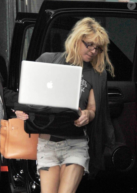 Courtney Love arrive avec ses chiens à Miami Beach et tente de se cacher derrière son ordinateur portable en juillet 2010