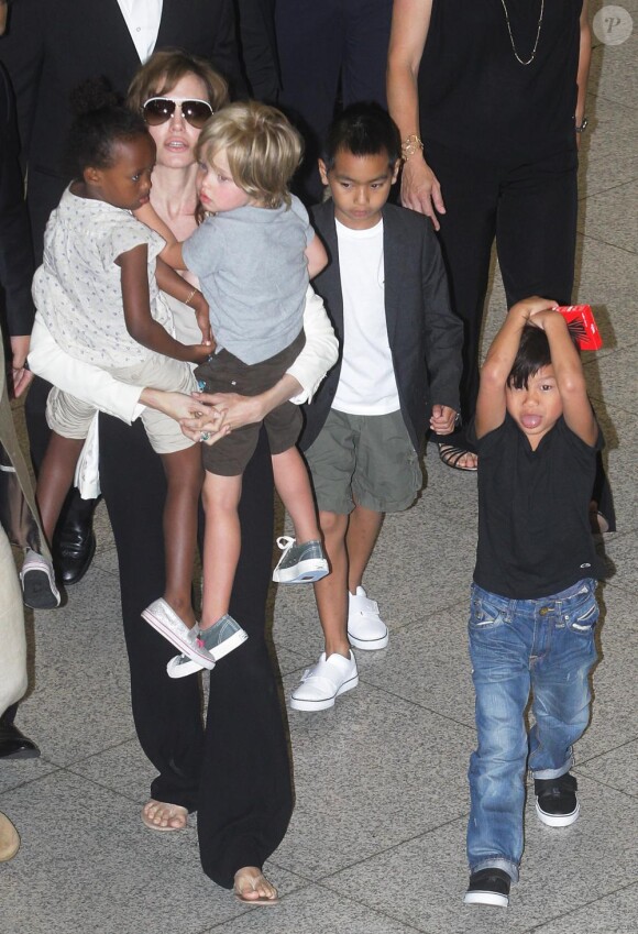Angelina Jolie portant ses filles Zahara et Shiloh, non loin de ses fils Maddox et Pax