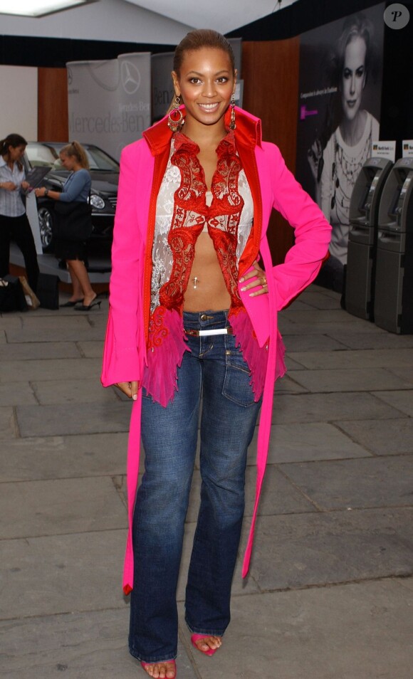 Beyoncé ose de porter une veste rose falshy avec une chemise à dentelles rouge et blanche qui dévoile son ventre musclé. Too much ! New York, 12 septembre 2003