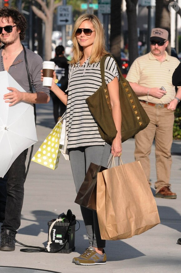 Les bras chargées de sacs et un café à la main, Heidi Klum shoote sa nouvelle campagne pour New Balance. Los Angeles, le 17 novembre 2011.