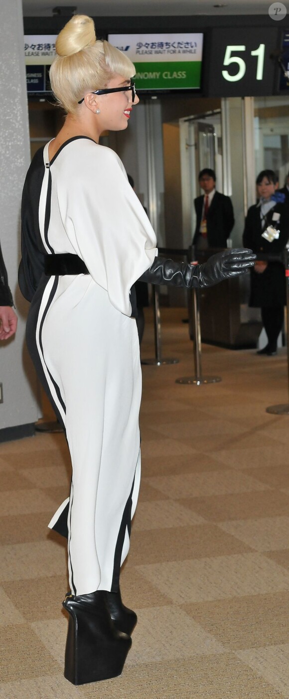 Lady Gaga, perchée sur ses gigantesques plateformes, salue ses fans à l'aéroport de Narita, le 24 décembre 2011.