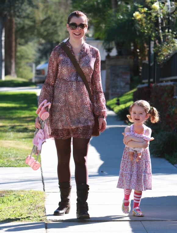 La poussette rangée, Satyana porte sa poupée dans ses bras, sous l'oeil avisé de sa mère Alyson Hannigan. Los Angeles, le 5 janvier 2012.