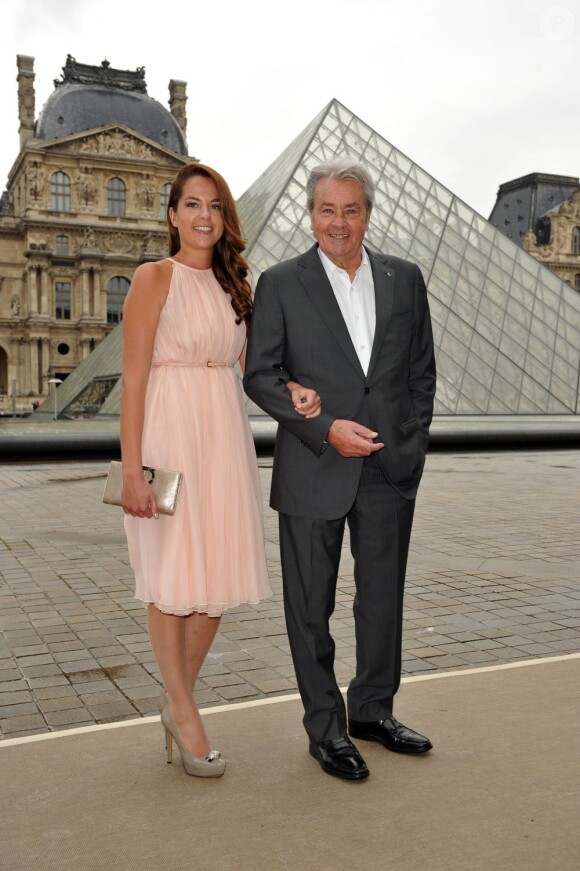 Anouchka Delon, au bras de son père Alain Delon, assiste au défilé Croisière 2013 de Salvatore Ferragamo à la Galerie Denon au Louvre. Paris, le 12 juin 2012.