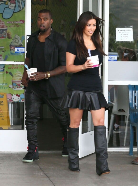 Kanye West suit des yeux sa belle Kim Kardashian, habillée comme lui en all black everything avec une mini-jupe en cuir et des bottes Givenchy. Hawaï, le 16 août 2012.