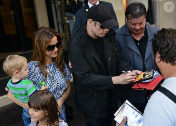 John Travolta et sa femme Kelly Preston : une douce balade à Paris avec leur enfant Benjamin, 22 mois, le 12 septembre 2012. La star trouve le temps de signer des autographes