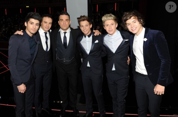 Les One Direction reçus par la reine Elizabeth II, accompagnés par Robbie Williams, à Londres le 19 novembre 2012