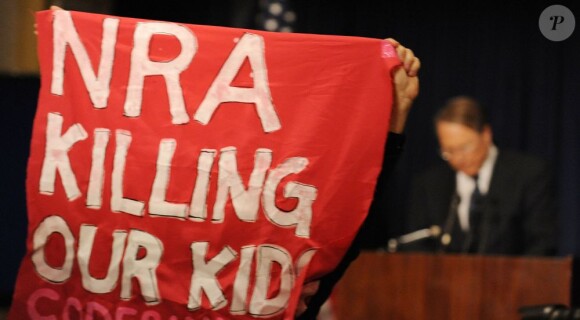 Le vice-président de la NRA Wayne LaPierre est interrompu durant son discours à l'hôtel Willard par un manifestant qui tient un carré en tissu sur lequel est inscrit "NRA Killing Our Kids". Washington, le 21 décembre 2012.