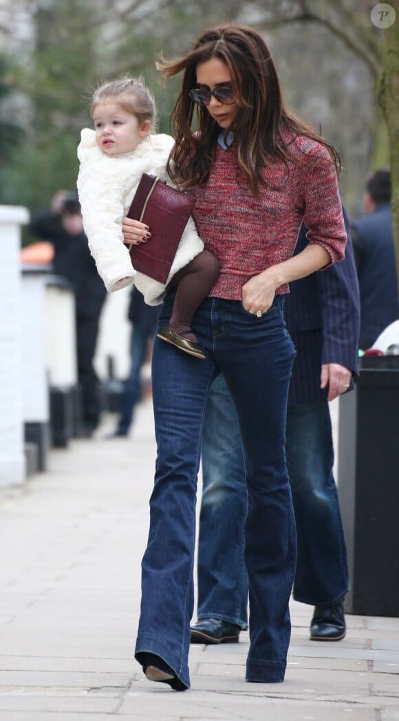 Victoria Beckham, maman preppy avec sa fille Harper, porte un sweater à col chemise Carven avec un jean flare et une pochette Victoria Beckham. Londres, le 26 mars 2013.