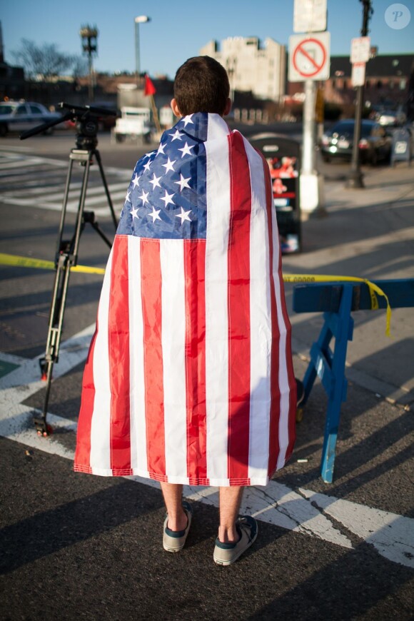 Image du drame du marathon de Boston qui a eu lieu le 15 avril 2013 : un étudiant porte le drapeau américain en hommage aux victimes