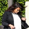 Kim Kardashian, enceinte et détendue à Los Angeles, porte avec son blazer noir et sa robe large blanche, un sac Hermès et des sandales Valentino. Le 28 mai 2013.
