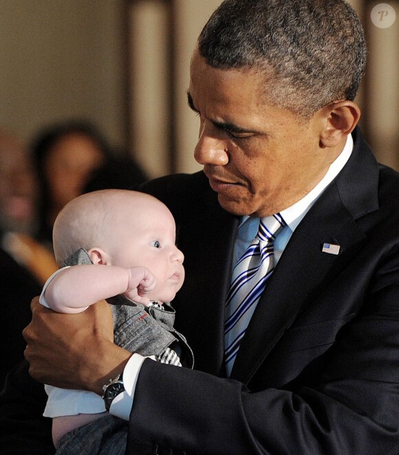 Barack Obama tient un bébé dans ses bras lors d'un déjeuner organisé à la Maison Blanche pour la Fête des pères à Washington, le 14 juin 2013. 2013.