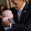 Barack Obama tient un bébé dans ses bras lors d'un déjeuner organisé à la Maison Blanche pour la Fête des pères à Washington, le 14 juin 2013. 2013.