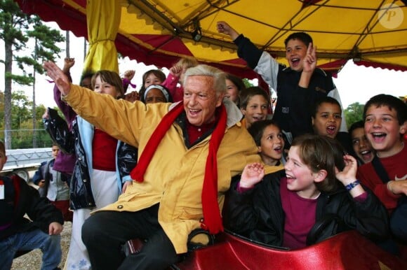 Guy Lux entouré d'enfants à la fête foraine de Boulogne grâce à son association Pas d'enfants sans vacances, octobre 2002.