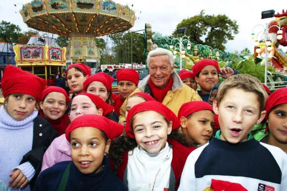 Guy Lux entouré d'enfants qu'il avait emmenés à la fête foraine de Boulogne grâce à son association Pas d'enfants sans vacances, octobre 2002.