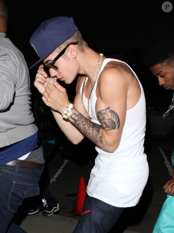 Justin Bieber se cache des photographes à la sortie du club "Milk Studios" à Hollywood, le 14 juin 2013.