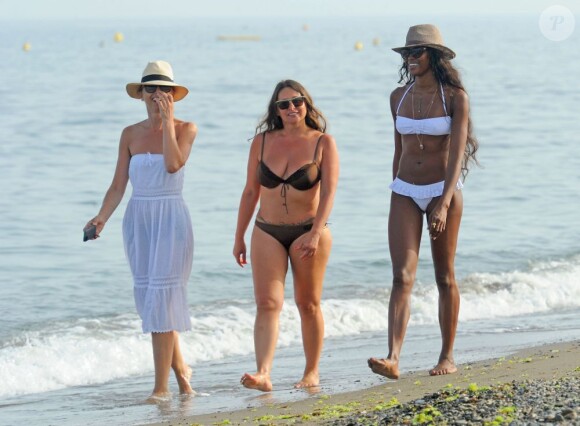Naomi Campbell, habillée d'un bikini blanc, se balade avec des amies sur une plage de Marbella. Le 4 août 2013.