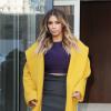 Kim Kardashian sort de l'appartement de son fiancé Kanye West à New York, habillée d'un manteau jaune en laine et angora Max Mara (collection automne-hiver 2013), d'un crop top violet, d'une jupe moulante Lanvin et de sandales Tom Ford. Le 20 novembre 2013.