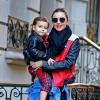 Miranda Kerr quitte son domicile en compagnie de son fils Flynn à New York, habillée de lunettes Prada, d'un perfecto Acne (modèle Merci Contrast), une chemise en jean nouée à la taille, un pantalon slim et des bottines noires. Le 16 novembre 2013.