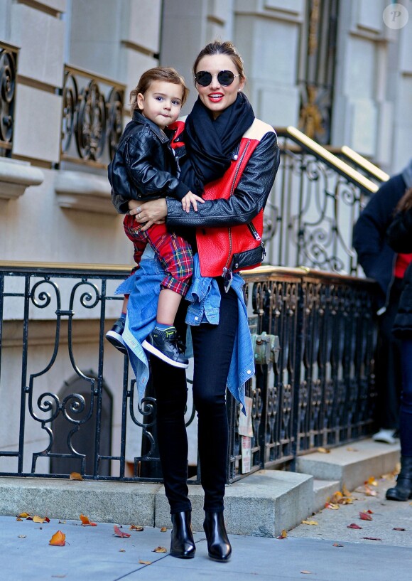 Miranda Kerr quitte son domicile en compagnie de son fils Flynn à New York, habillée de lunettes Prada, d'un perfecto Acne (modèle Merci Contrast), une chemise en jean nouée à la taille, un pantalon slim et des bottines noires. Le 16 novembre 2013.