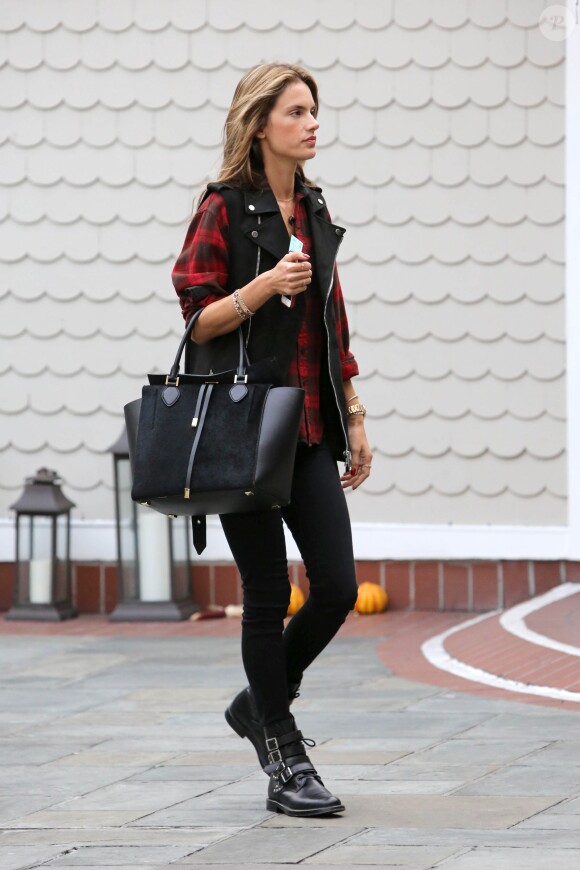 Alessandra Ambrosio surprise à Santa Monica, porte un sac Michael Kors (modèle Miranda) et des bottes à sangles Saint Laurent avec un slim noir, une veste biker sans manches et une chemise à carreaux. Los Angeles, le 21 novembre 2013.